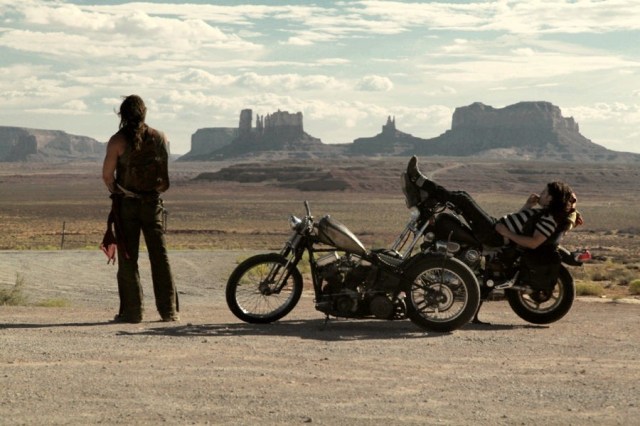 wide angle of two bikers looking out at Monument Valley in the desert.